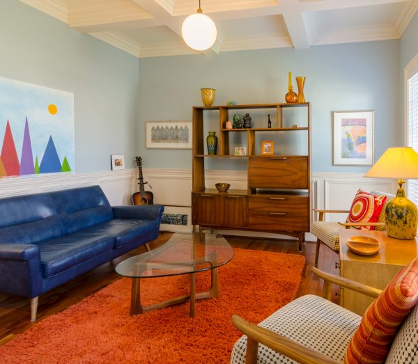 Image of bright colored living room with blue couch, coffee table, and wooden book case